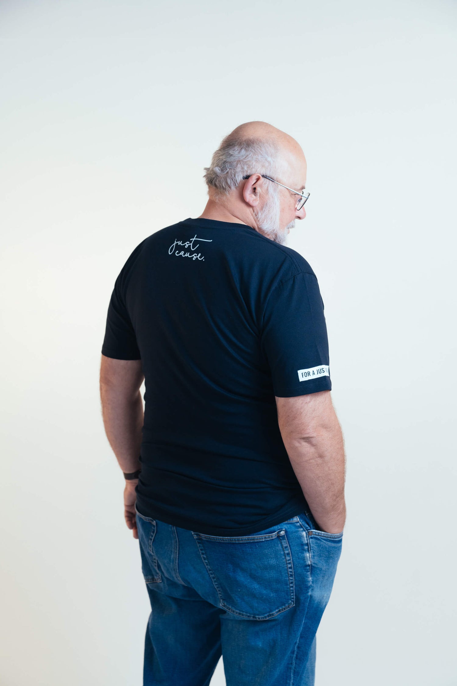 Steve, facing away from the camera wearing an ink blue tshirt with the Just Cause logo on the back and the words 'For a Just World' on the armsleeve written in white.